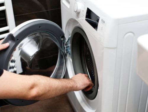 Man opens washing machine in bathroom at home